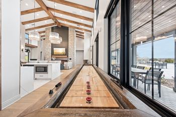 A long wooden table with bowling pins on it is in the middle of a modern kitchen and dining room.